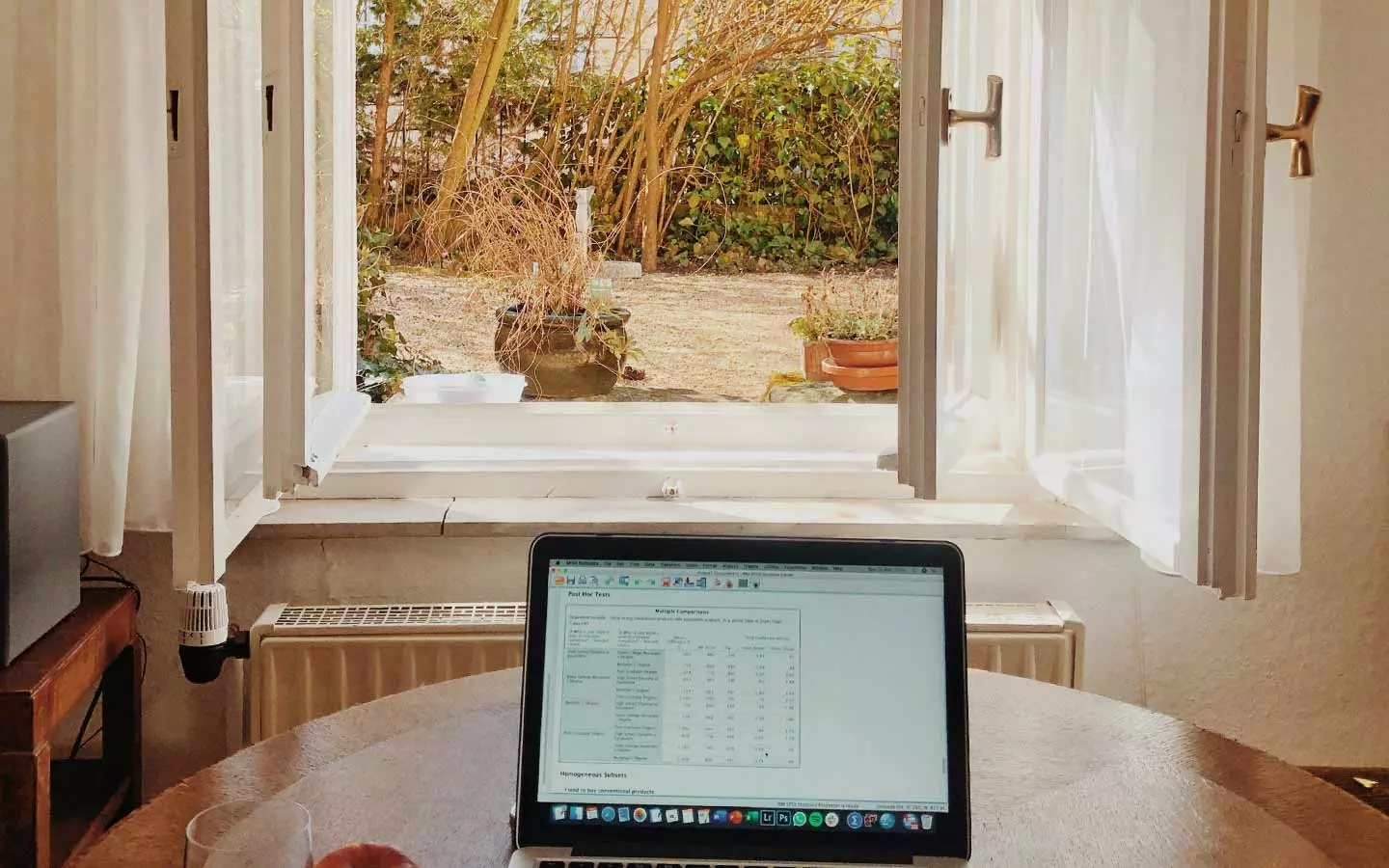 aktiver Laptop auf einem Zimmertisch vor geöffnetem Fenster