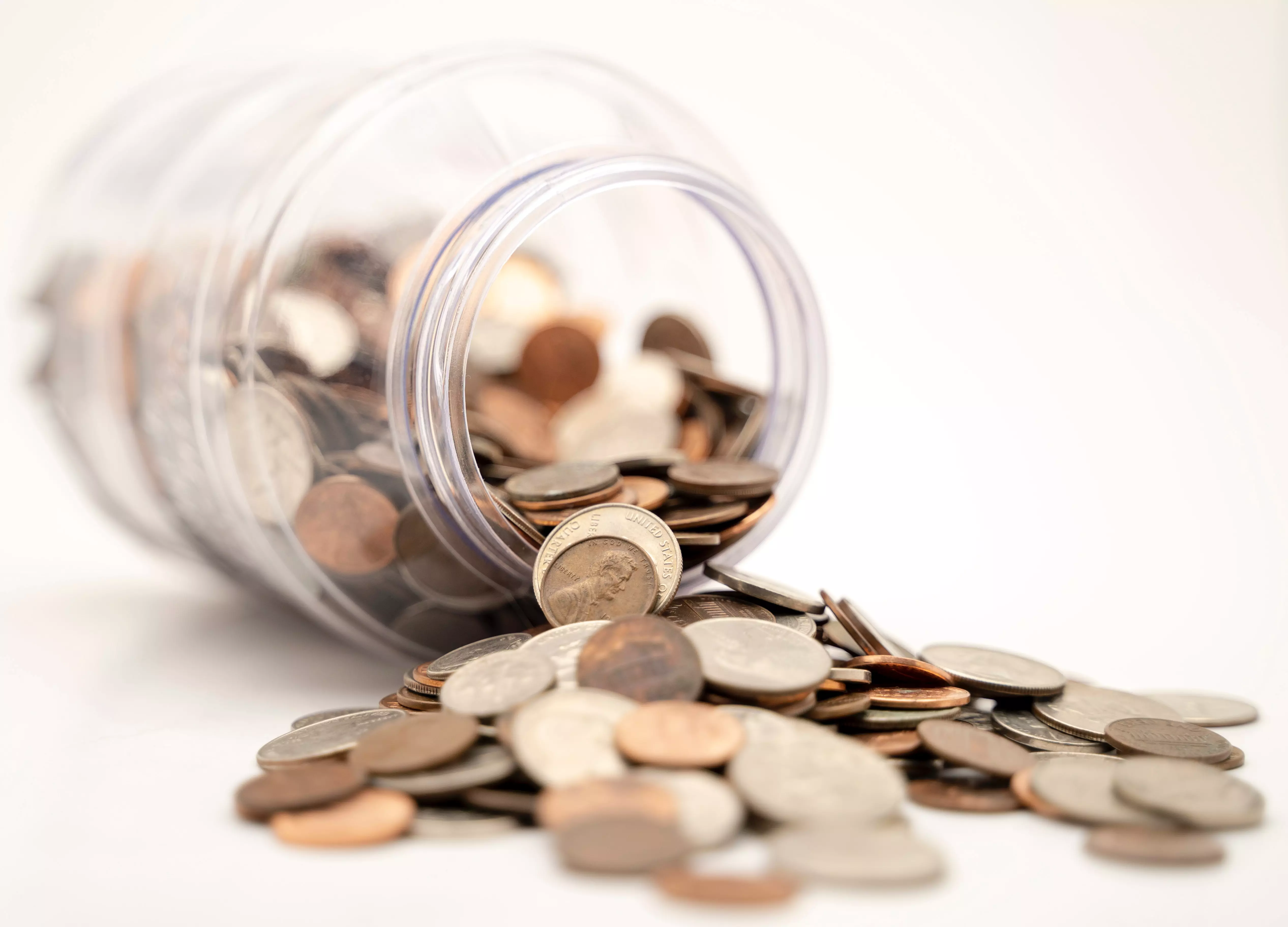 gekippter Glasbehälter mit teilweise herausgeschütteten Kleingeldmünzen