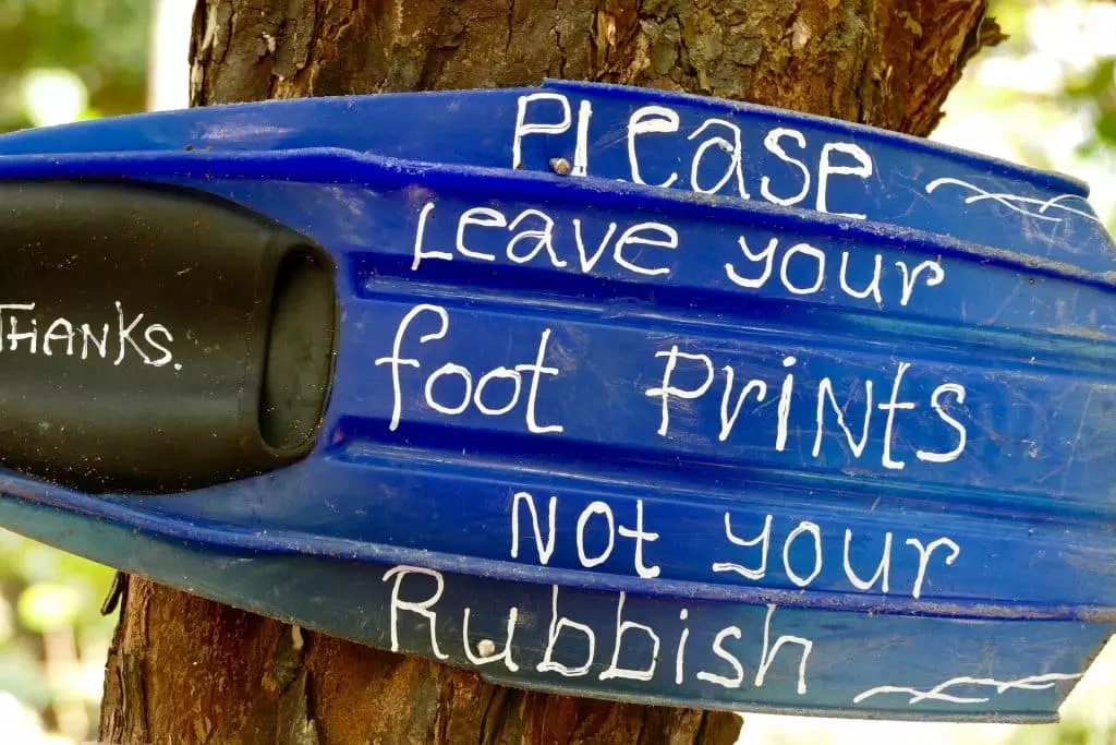 Fußabdrücke statt Plastik englischer Slogan geschrieben auf einer Taucherflosse an einem Baum hängend