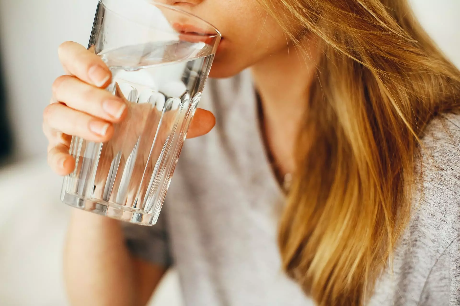 Frau mit an den Lippen angesetztem Wasserglas